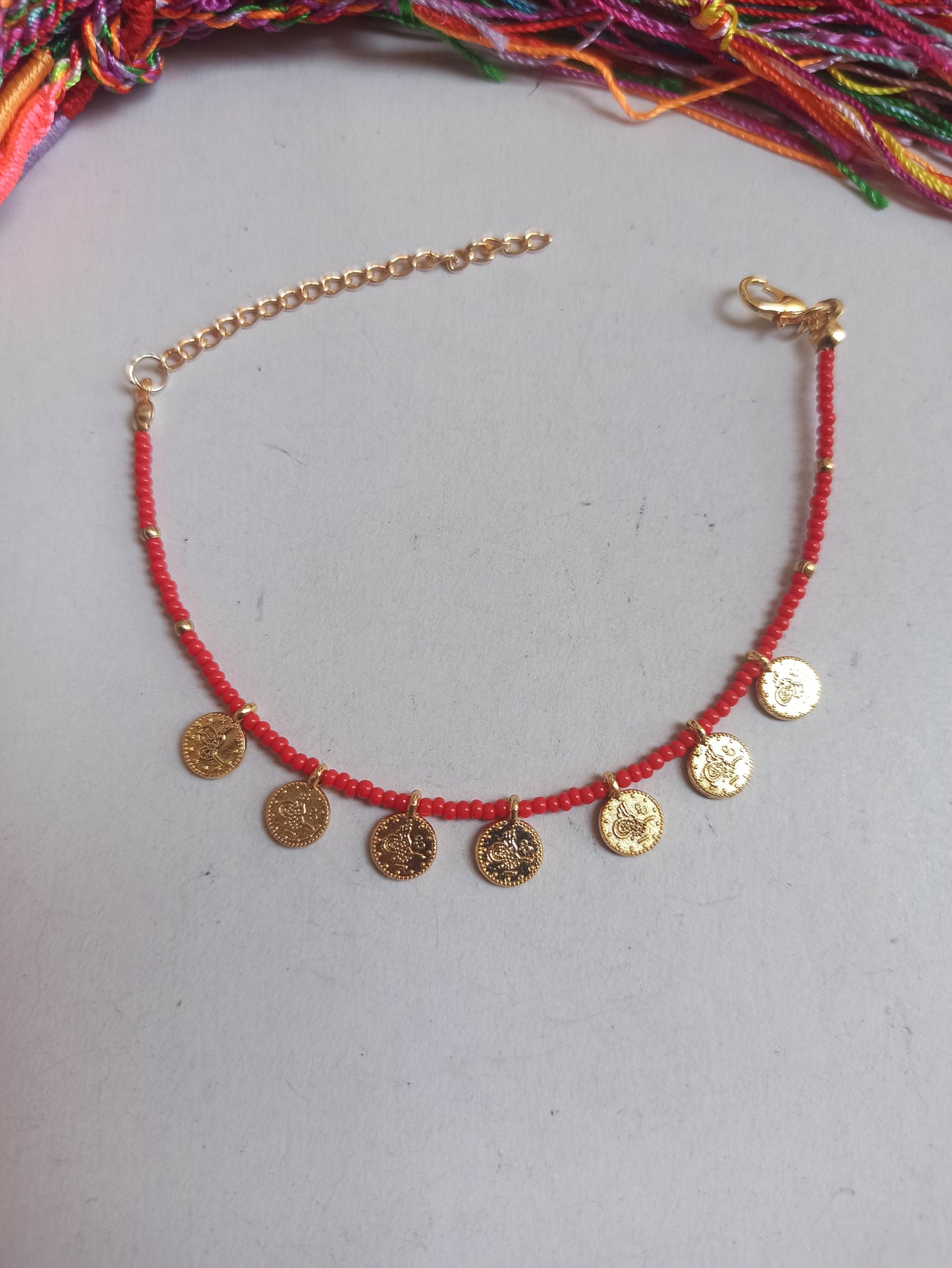 Thin beaded bracelet with red coins